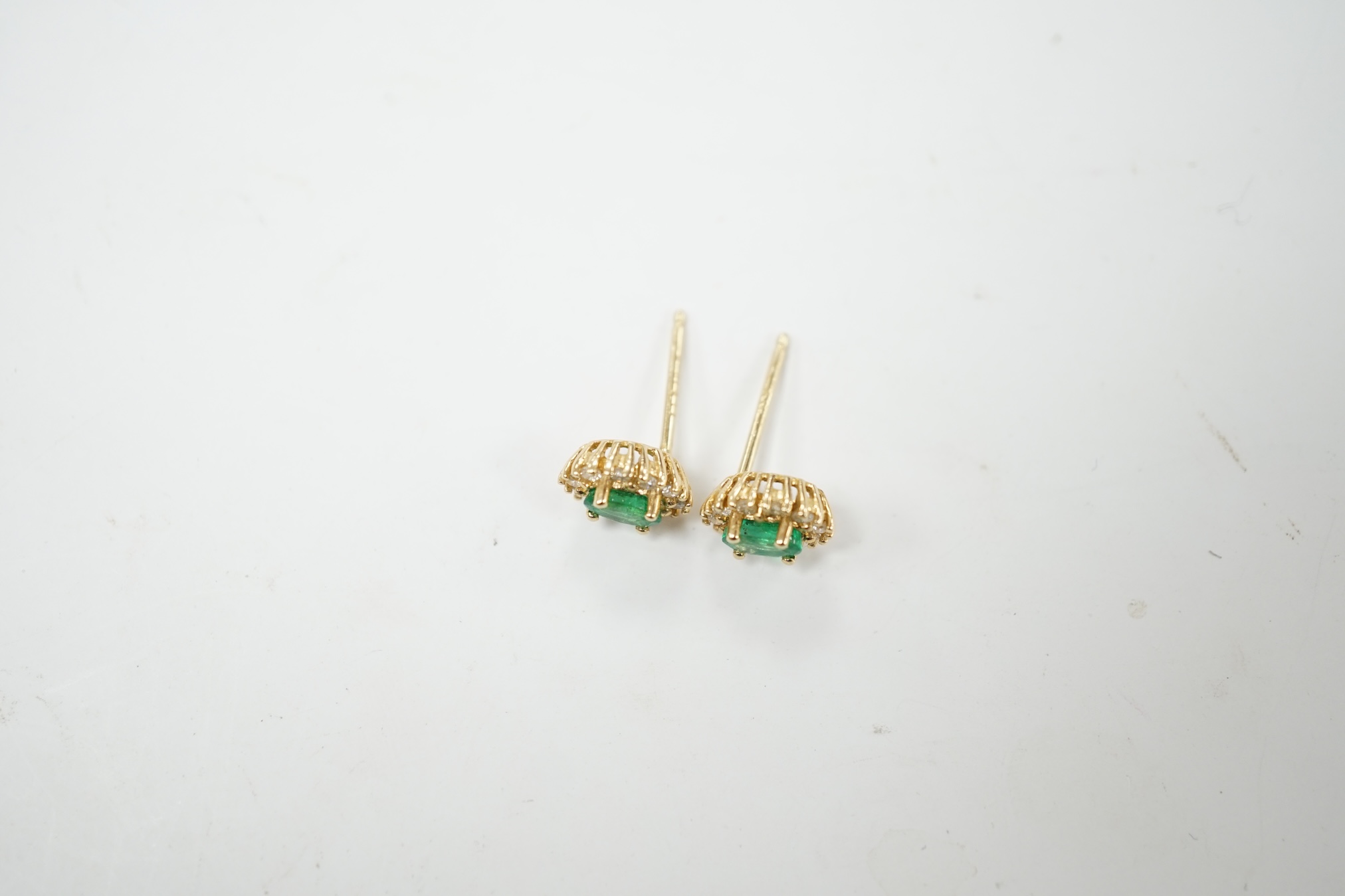 A modern pair of 14k, emerald and diamond set oval cluster ear studs, 8mm, gross weight 1.4 grams. Condition - fair